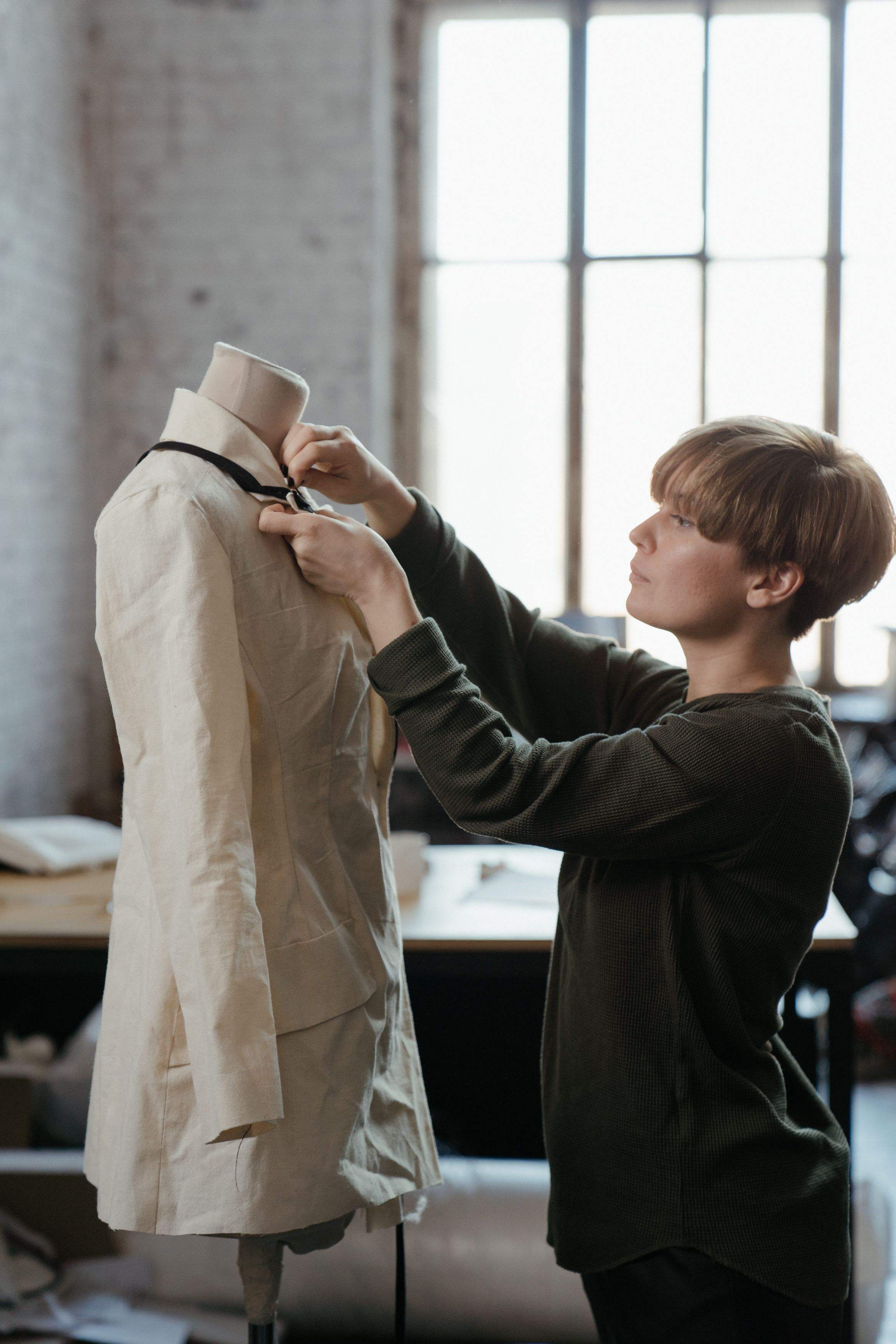 A designer adjusting a muslin jacket on a dress form