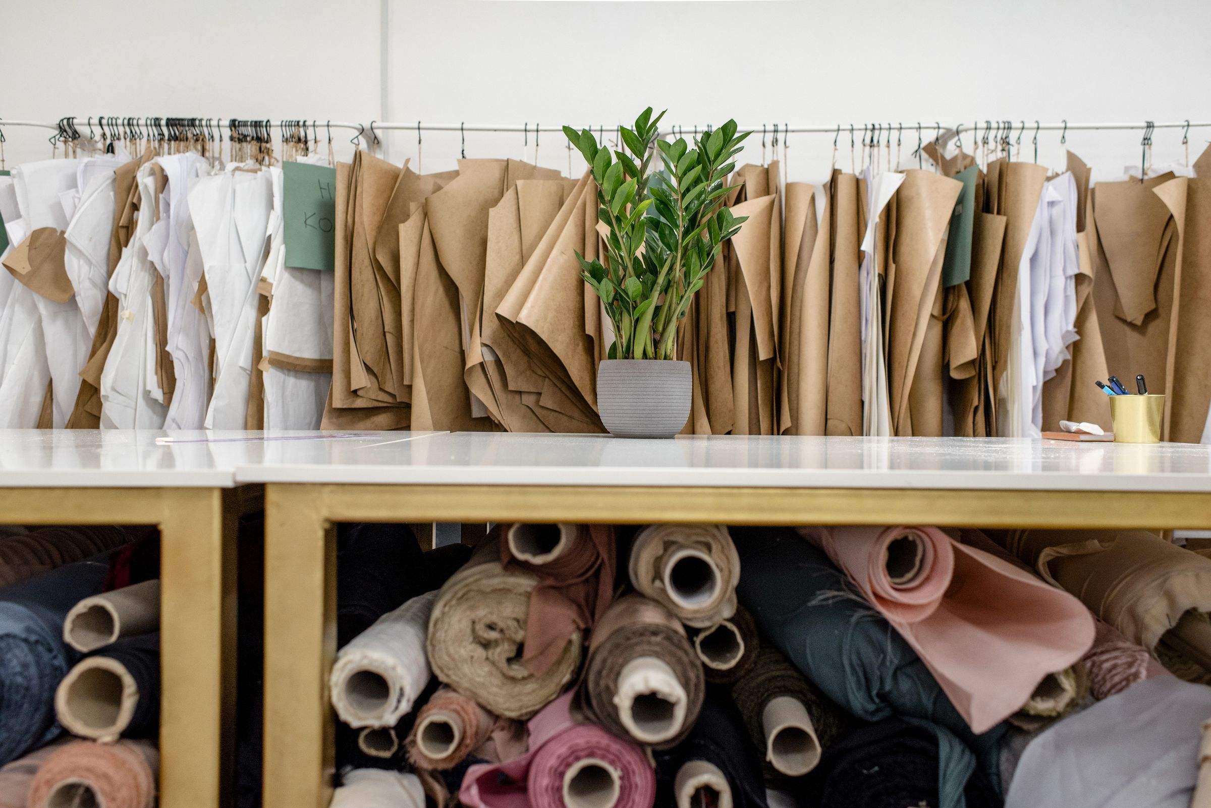 Fabric rolls stored beneath a cutting table and pattern rail