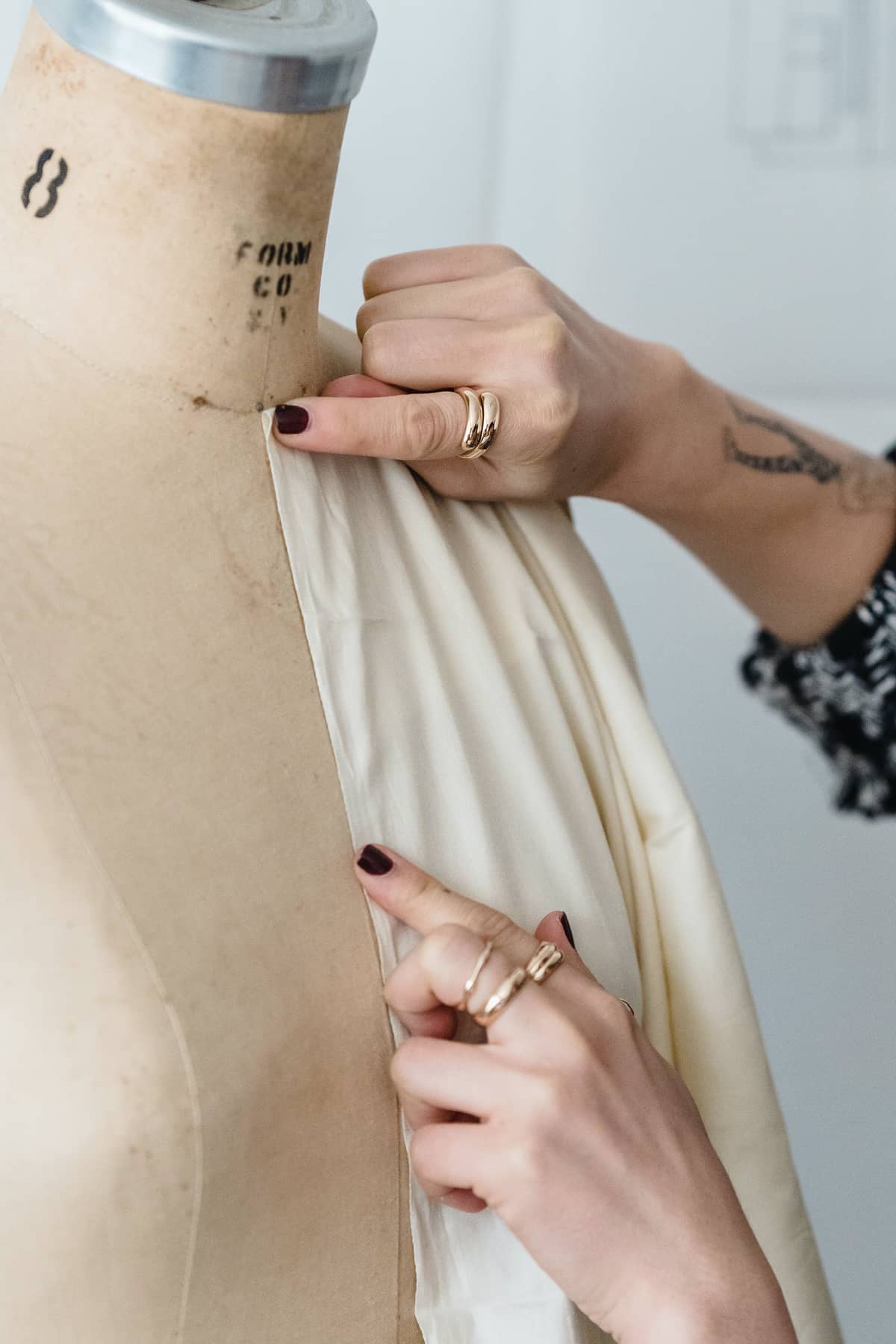 Smoothing cream fabric over a numbered dress form