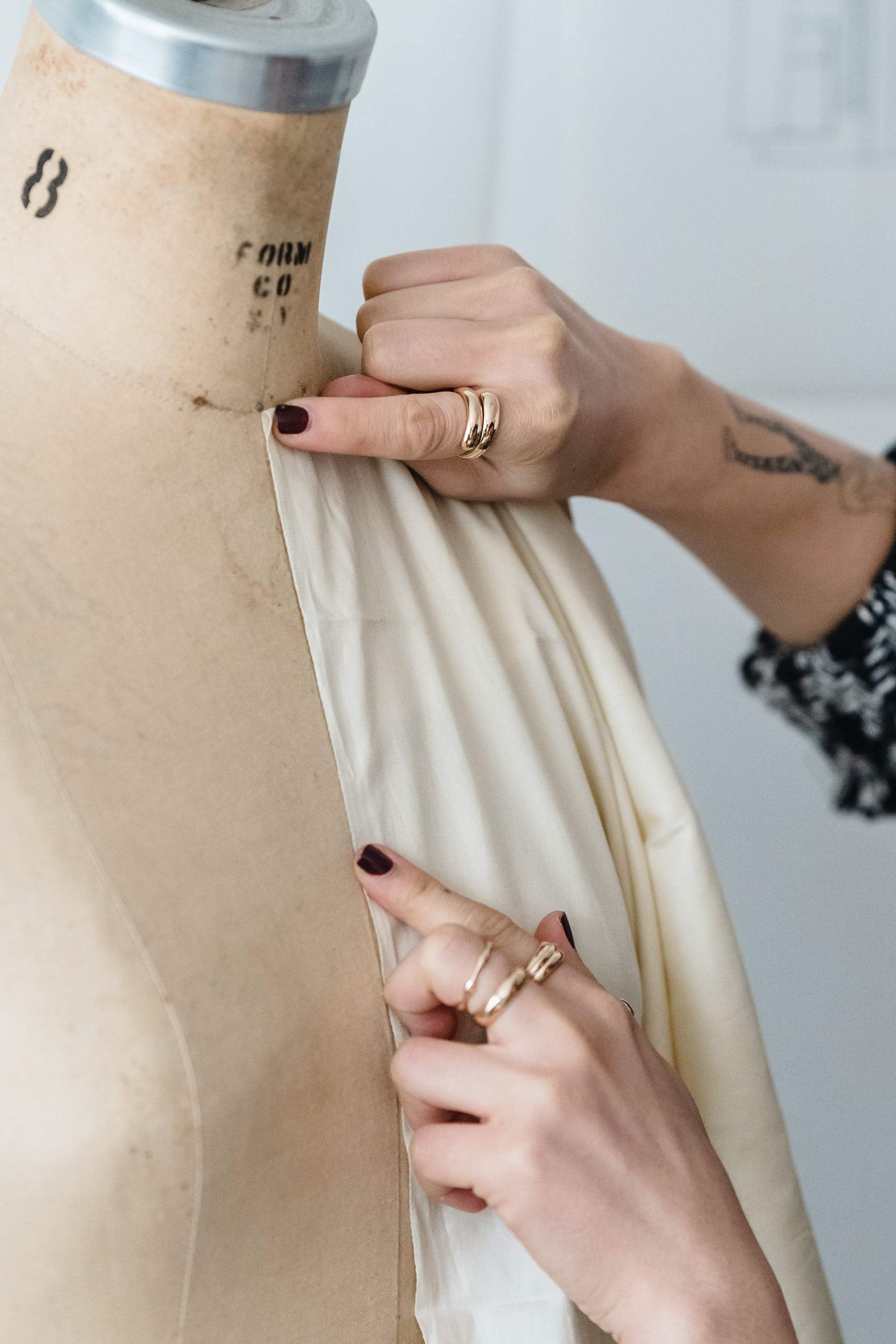 Smoothing cream fabric over a numbered dress form