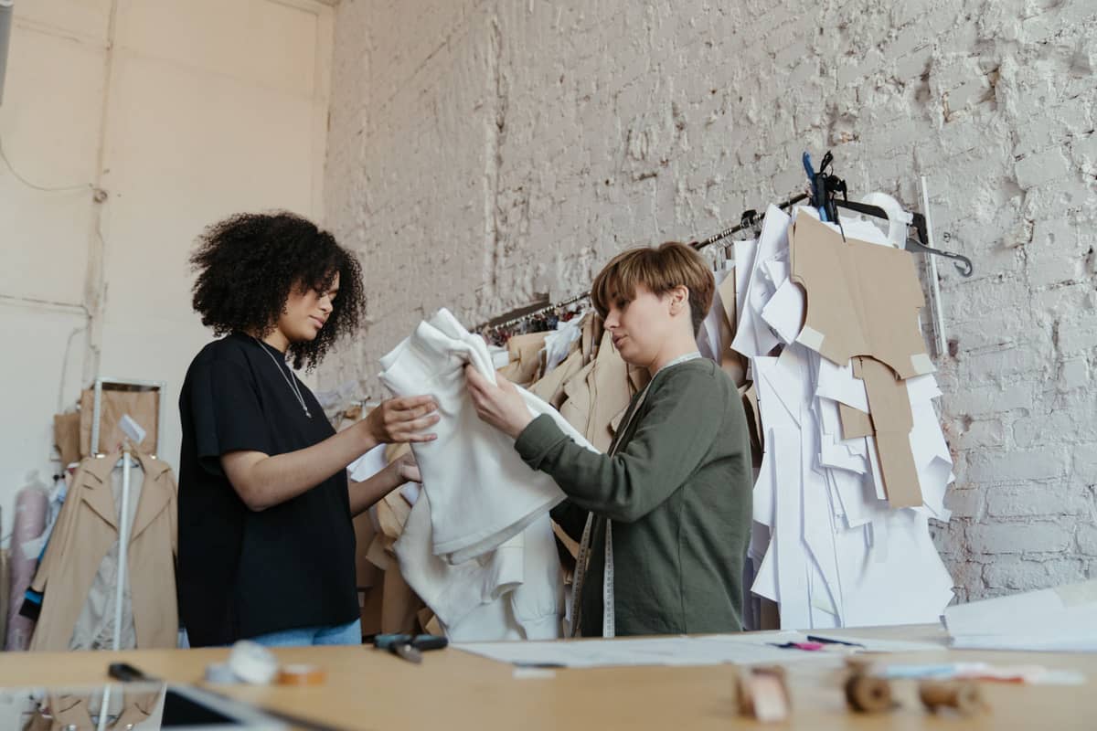 Two designers reviewing a garment beside the pattern rack