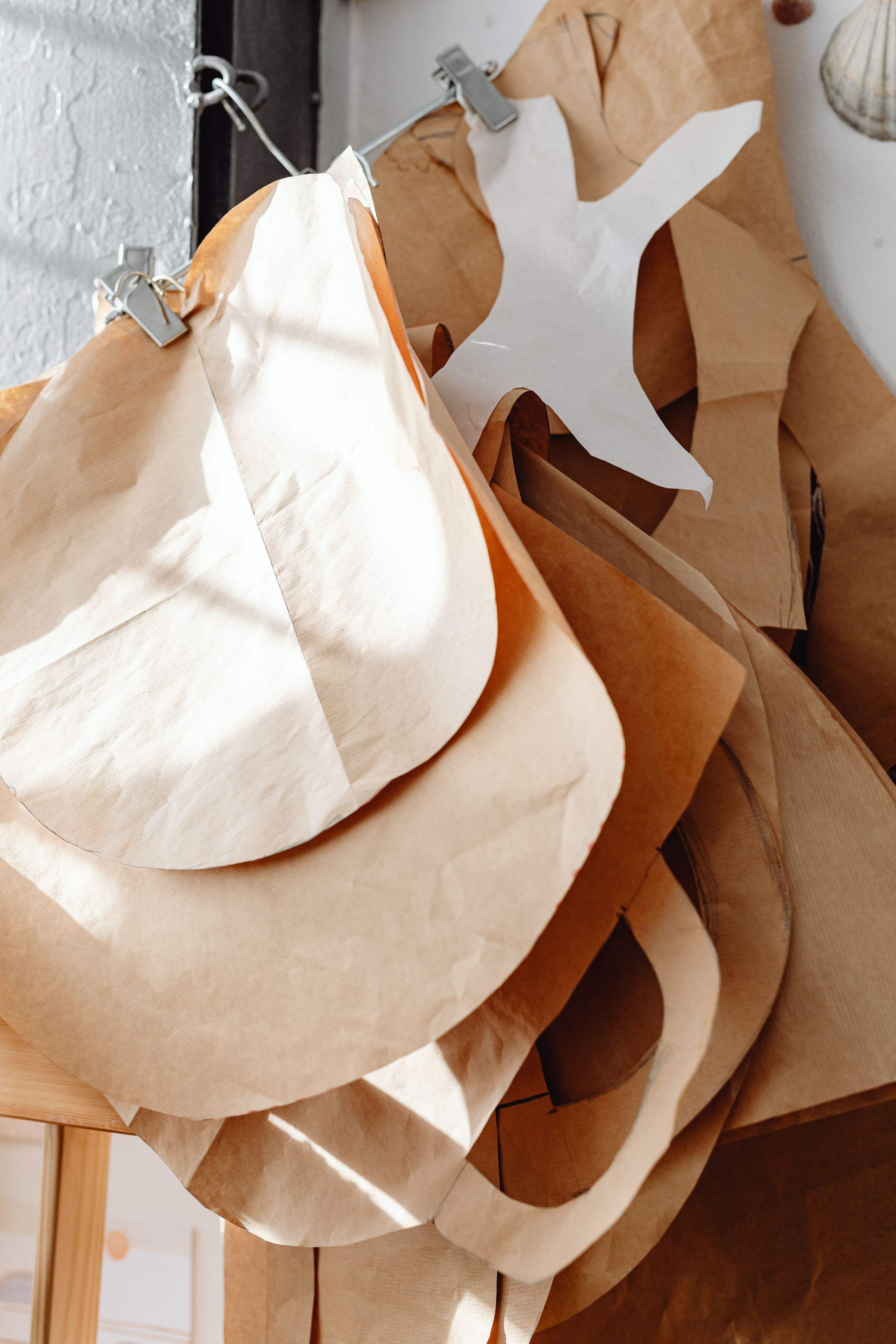 Kraft and muslin pattern pieces hanging in sunlight