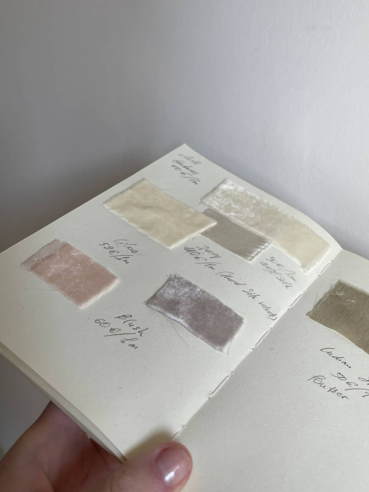 A notebook of fabric swatches with handwritten notes