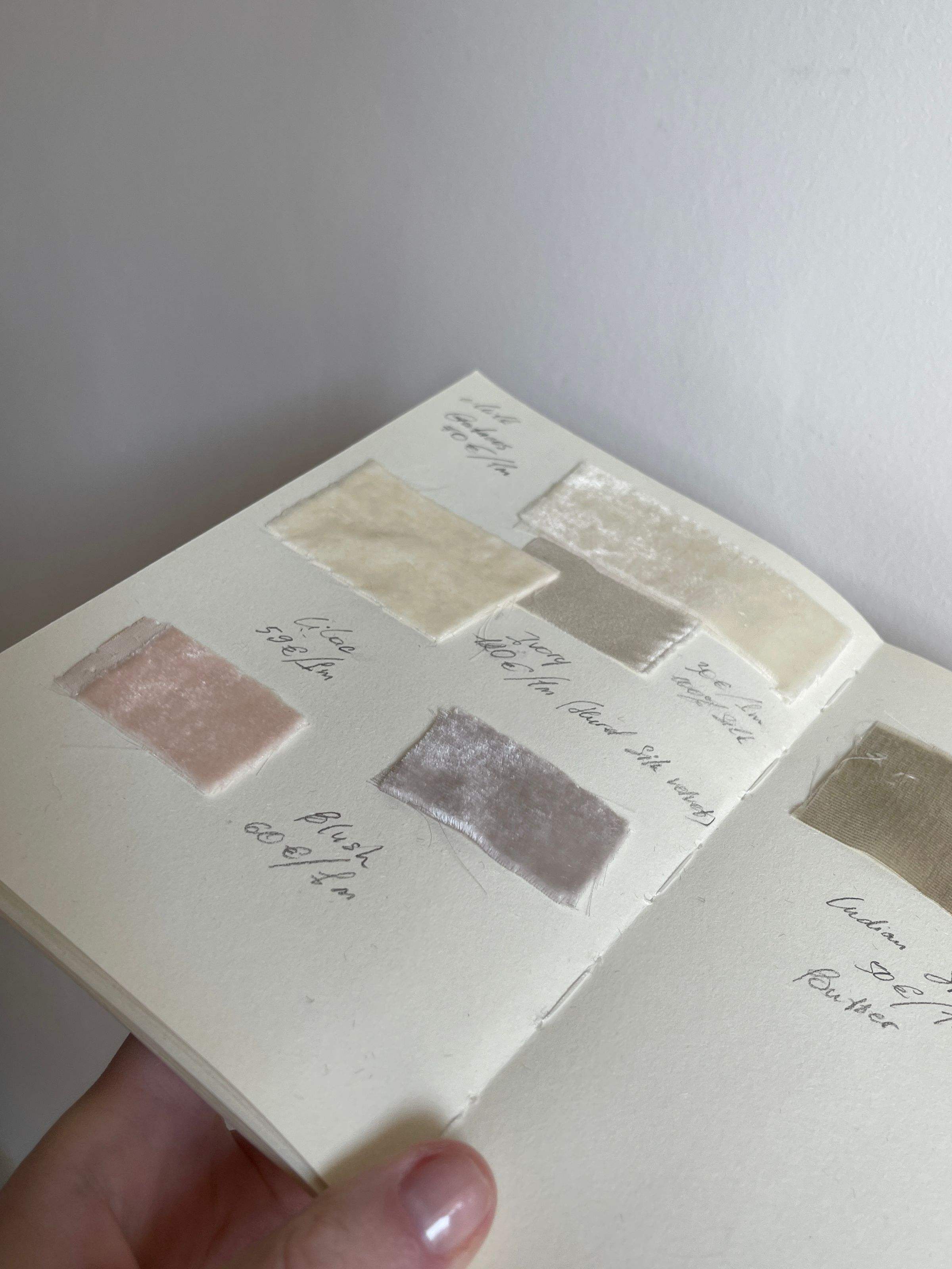 A notebook of fabric swatches with handwritten notes
